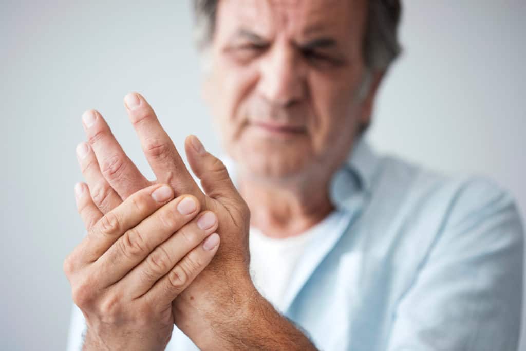 older man holding his hand in need of treatment for chronic pain