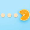 Vitamin C supplements pills with Orange Fruit Cross Section isolated on blue background. Vitamin deficiency, avitaminosis concept. Homeopathy cure treatment, to show how much vitamin c when sick should i take