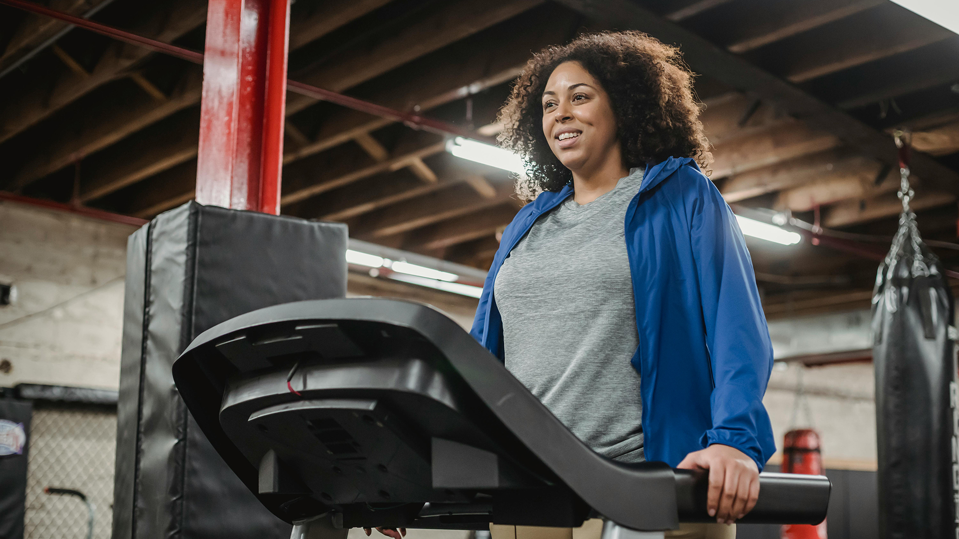 A confident woman smiling while walking on a treadmill, prioritizing joint health by participating in daily exercise.