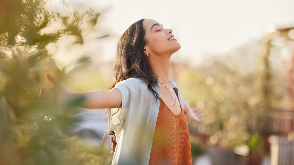 A woman exhaling and smiling with her head tossed back, expressing gratitude, showing what is gratitude.